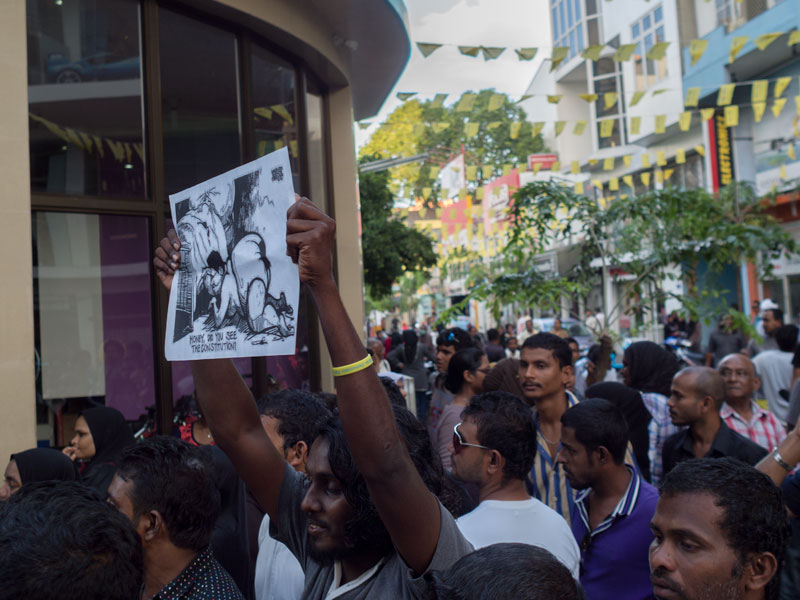 Protesters near Supreme Court hold up cartoons making fun of disgraced Justice Ali Hameed Photo: Aznym